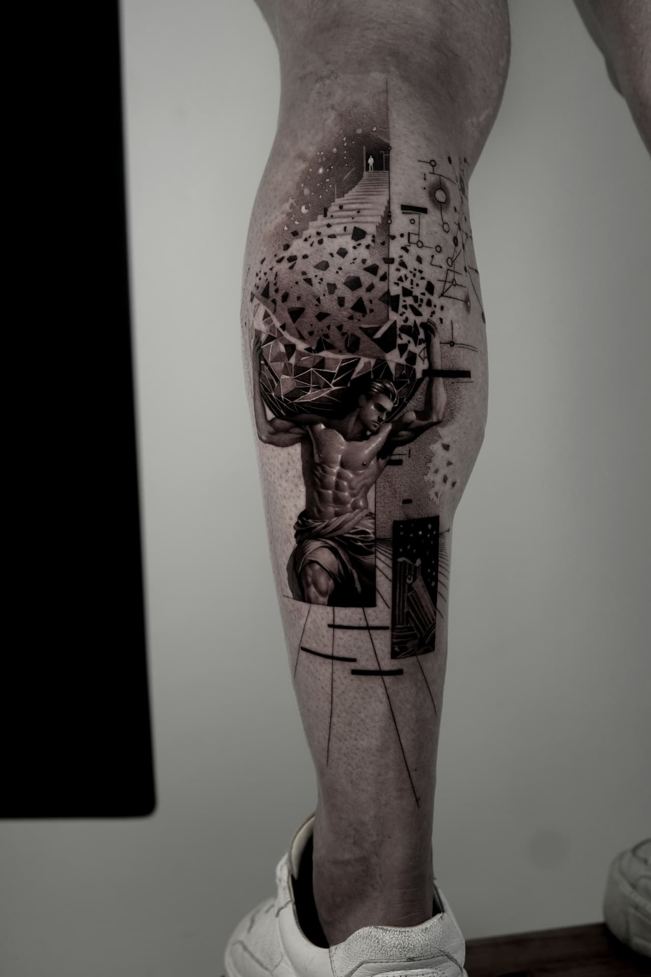 Tatuagem de Atlas em preto e cinza na panturrilha